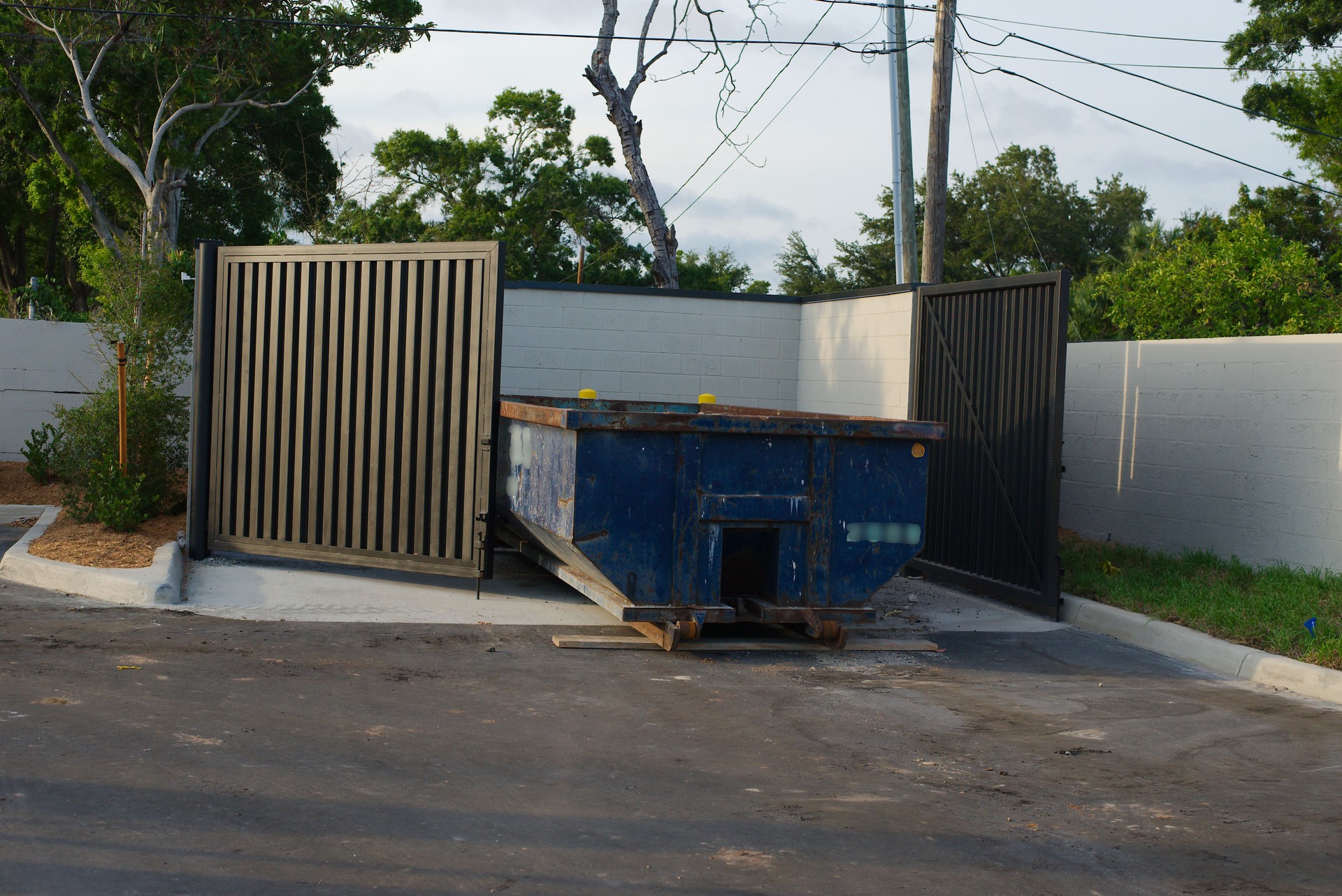 Blue Dumpster Enclosed in a Designated Garbage Disposal Area Outdoors